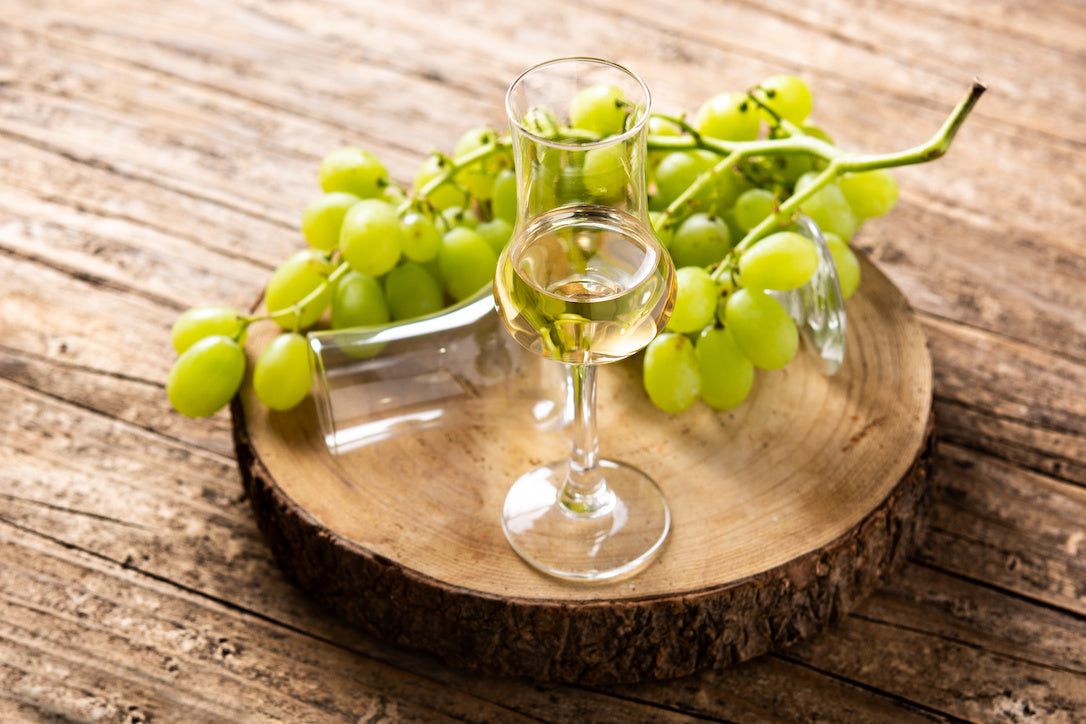木製のテーブルに置かれた白葡萄とグラッパ