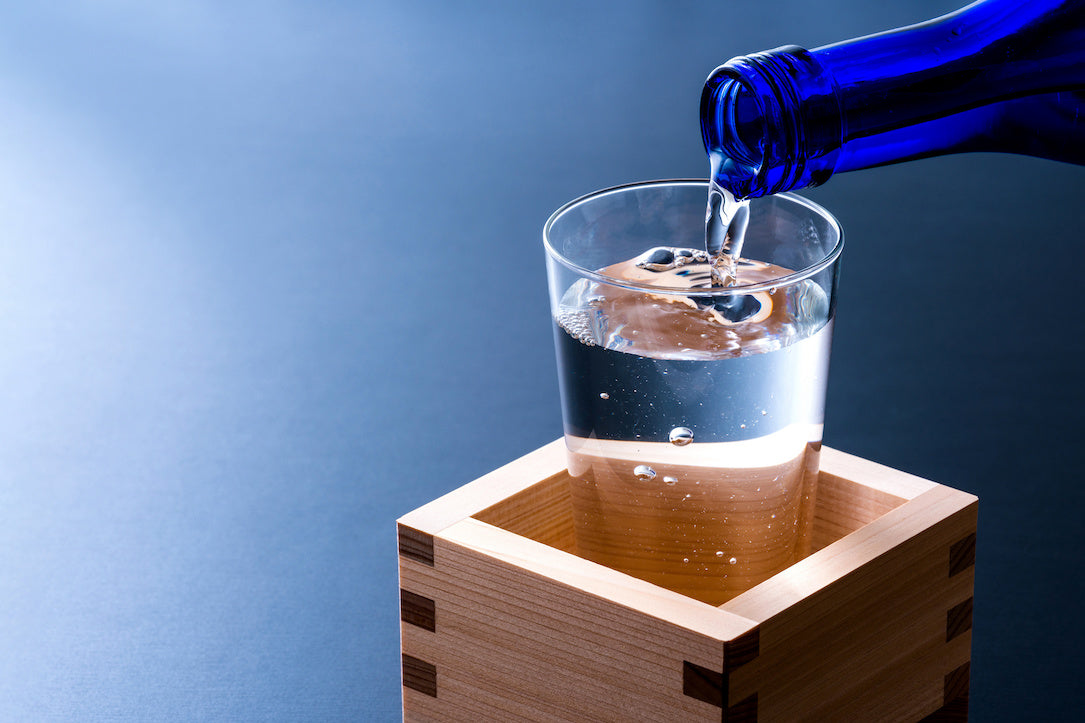 升の中に置かれたグラスに日本酒を注ぐ