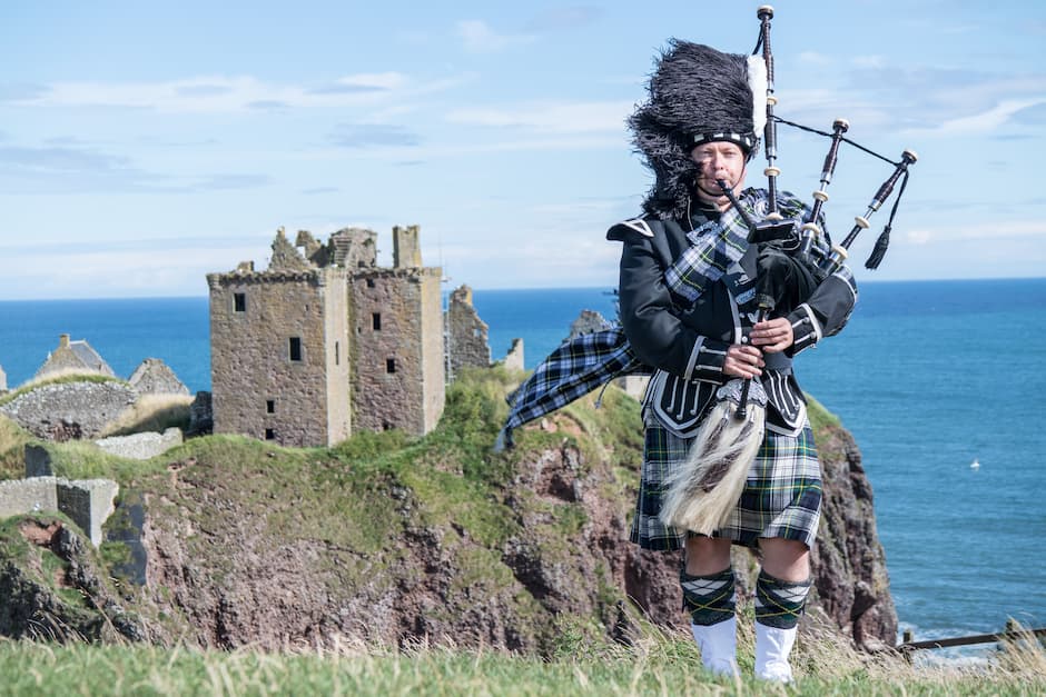 ダノター城で伝統的スコットランド衣装を着たパイプ奏者